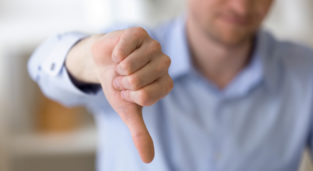 Dissatisfied business man showing thumbs down at workplace Thumbs down